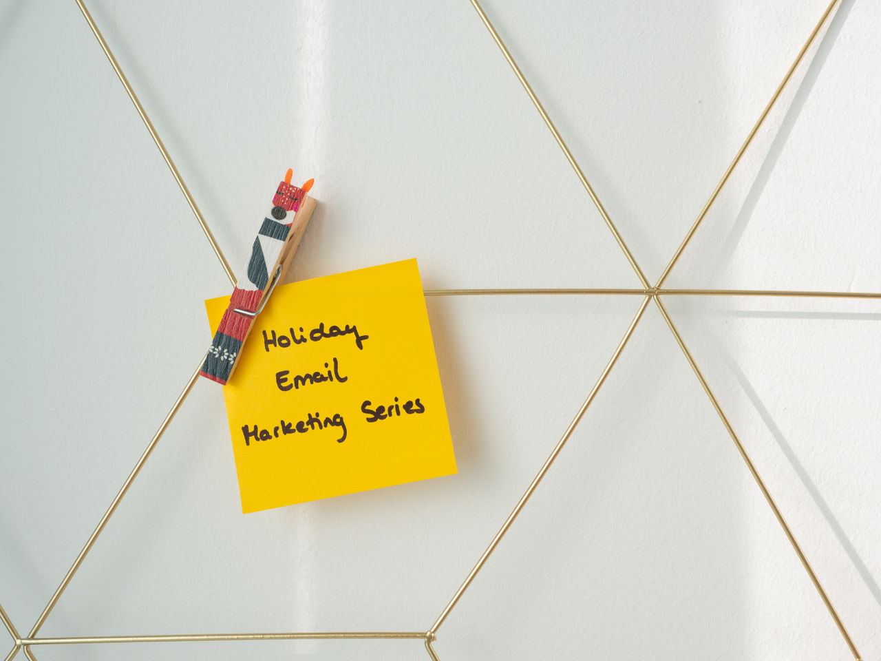 about-01 A bright yellow sticky note clipped to a wireframe wall, carrying a holiday email marketing message.